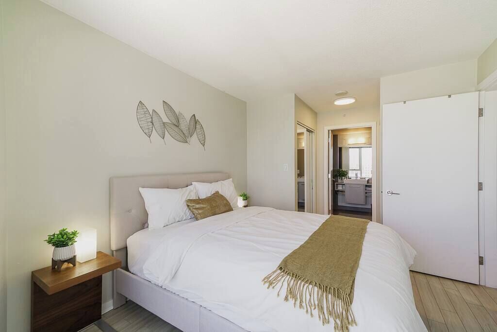 A bedroom with a bed, bedside table, and a wall-mounted artwork.
