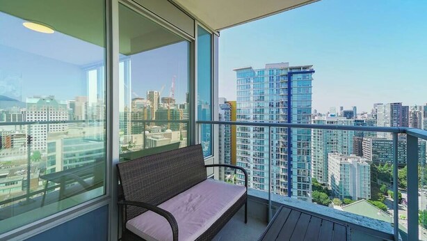 A balcony with a wicker chair and a view of a cityscape.