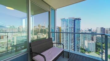 Ein Balkon mit Korbstuhl und Blick auf die Stadtlandschaft.