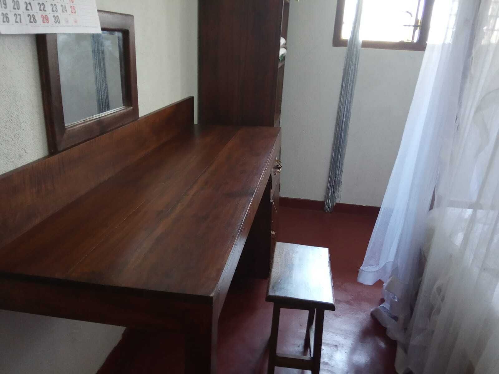 A room with a wooden bench, a small table, and a calendar on the wall.