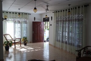 A spacious room with tiled flooring, a wooden door, and a chair. - Villa Joana Ahangama Sri Lanka (Ahangama)