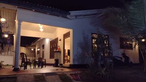 A well-lit outdoor area with a patio, seating, and a pathway leading to a building.
