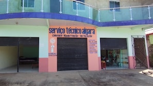 Un edificio con un letrero que dice "servico tecnico algara" y una puerta con persiana cerrada.