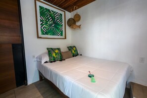 A bedroom with a bed, pillows, a wall art piece, and a hanging decoration. - Amaia Boutique Hotel - Economy Double Room (Sayulita)