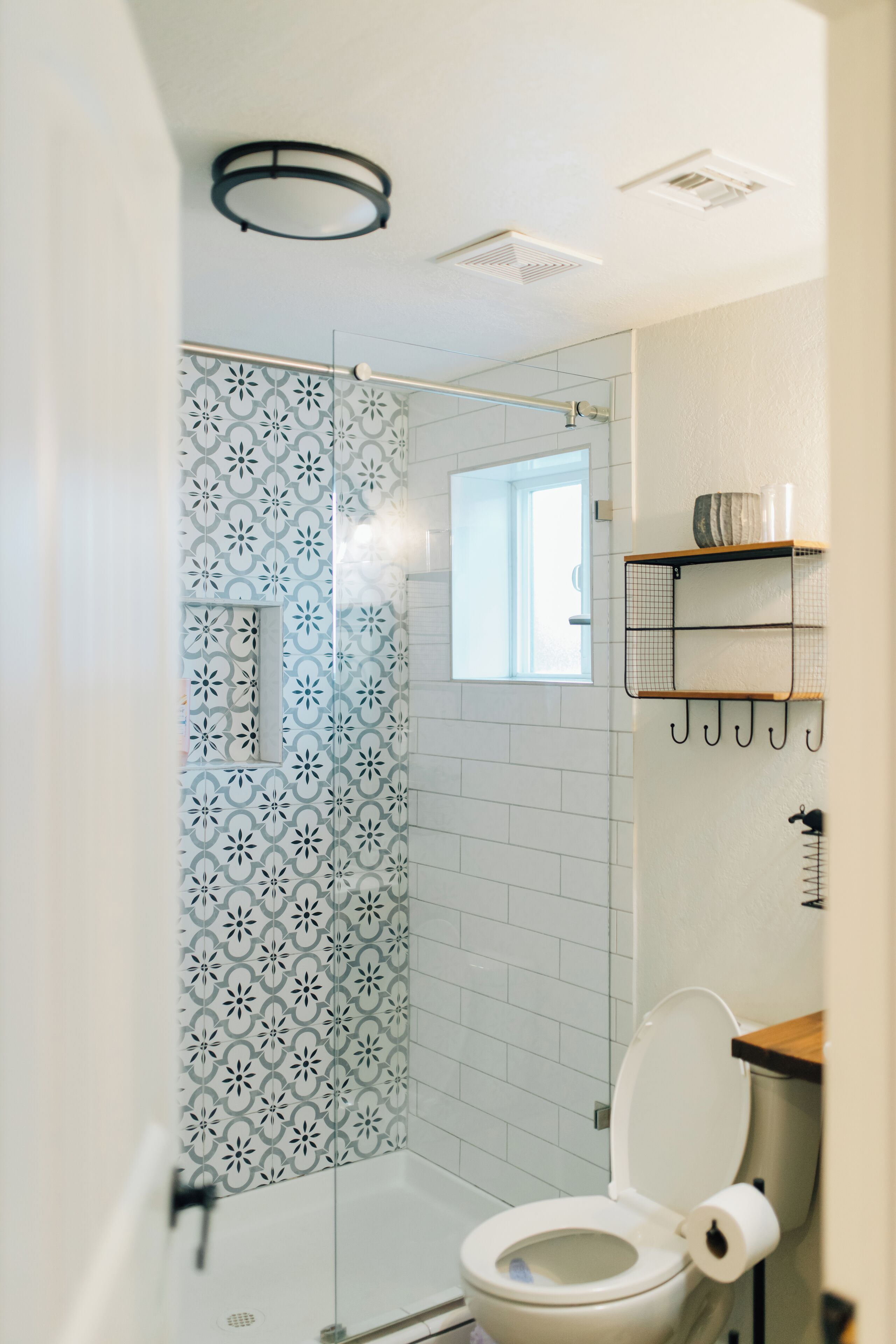A bathroom with a shower, toilet, and a window.