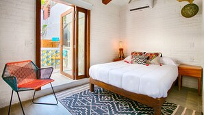 Un dormitorio con cama, una silla, una mesita de noche y ventana con vistas al exterior.