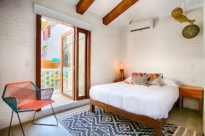 A bedroom with a bed, a chair, a bedside table, and a window.