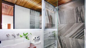 Une salle de bain moderne avec une grande baignoire, une douche avec des portes en verre et des carreaux de marbre.