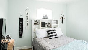 Une chambre à coucher avec un lit, une commode blanche, un miroir et un ventilateur de plafond.