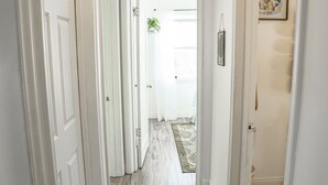 Un couloir avec des portes blanches, un tapis à motifs et un tableau encadré accroché au mur.