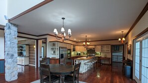 Une cuisine spacieuse avec un îlot central, un plancher en bois et un lustre.