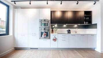 A modern kitchen with white cabinets, a built-in oven, and a window providing natural light.
