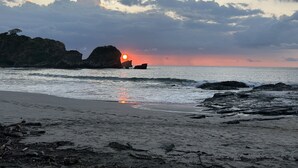 A beach with rocky formations and a sunset.