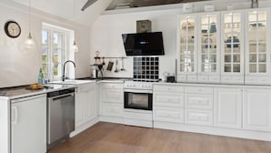 A modern kitchen with white cabinetry, a built-in oven, a stove, and a large window providing natural light. - 2 bedroom pet friendly home in ålbæk (Ålbæk)
