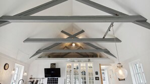 A spacious room with exposed wooden beams, a built-in kitchen with cabinets, and pendant lighting. - 2 bedroom pet friendly home in ålbæk (Ålbæk)
