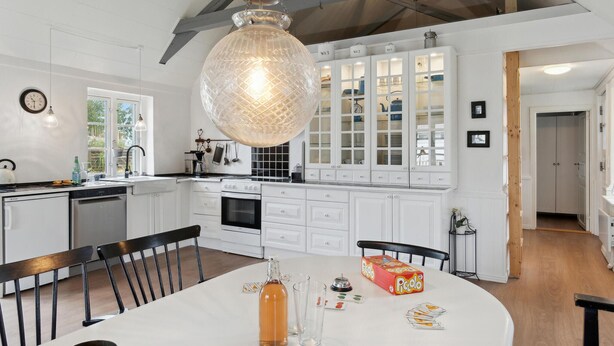 A modern kitchen with white cabinetry, a large pendant light, and a dining area with a table set for two. - 2 bedroom pet friendly home in ålbæk (Ålbæk)