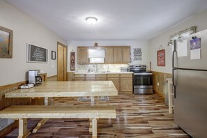 A kitchen with wooden cabinets, a stainless steel refrigerator, a wooden dining table, and a built-in oven. - Lakefront Phelps Cabin w/ Boat Dock & Water Toys! (Phelps)