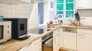 Une cuisine moderne avec des meubles blancs, une machine à café Bosch, un lave-vaisselle Siemens et une fenêtre donnant sur un paysage verdoyant.