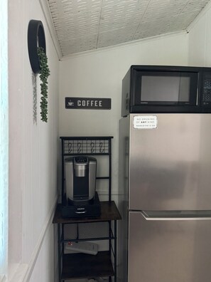 Una kitchenette equipada con cafetera, microondas y refrigerador.