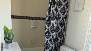 Une salle de bain avec un lavabo blanc, des toilettes et un rideau de douche.