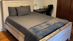 Une chambre à coucher comprenant un lit, un bureau, une chaise, un ventilateur de plafond et une porte.