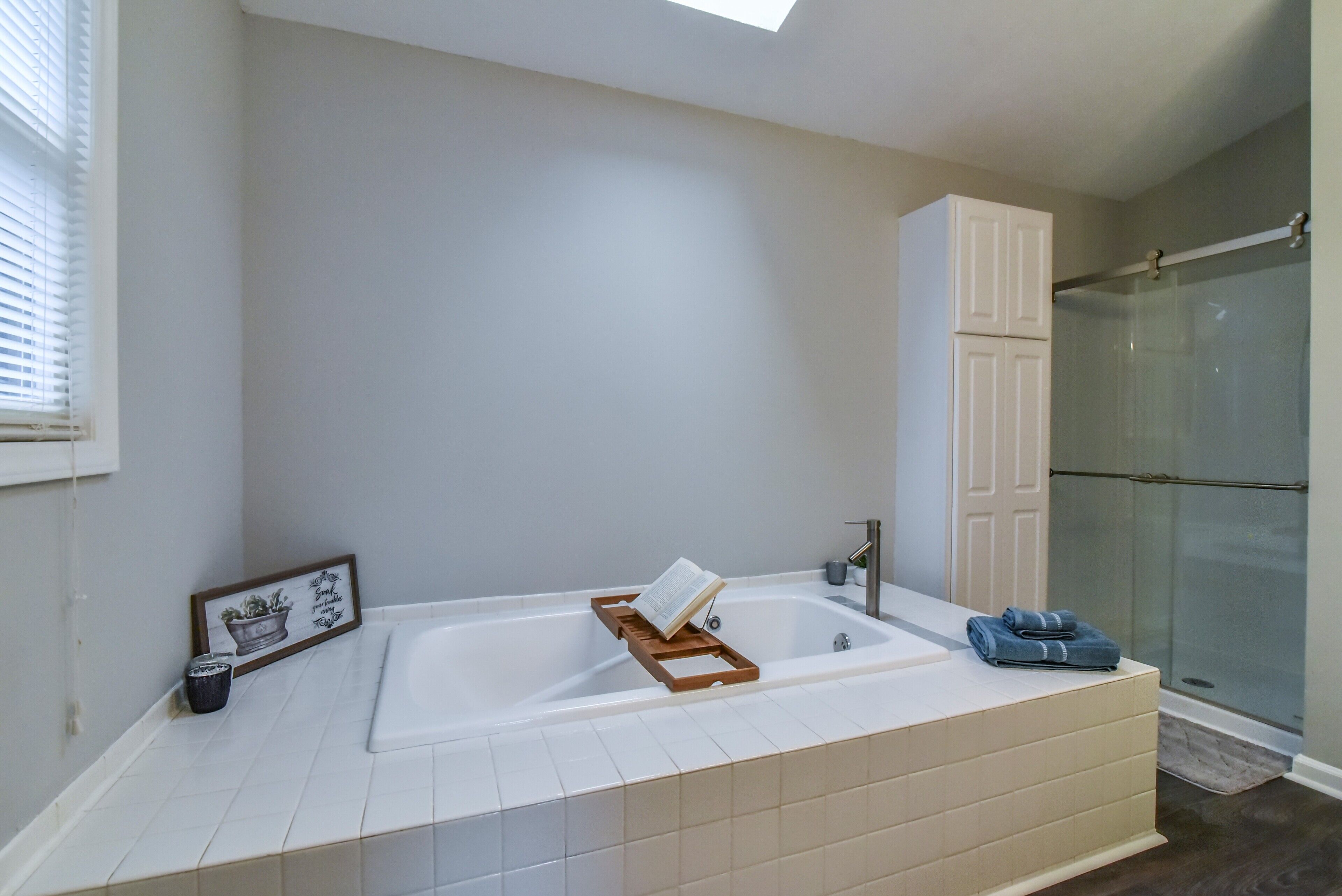 Een moderne badkamer met een groot bad, een douche en een wastafel met een handdoekhouder.