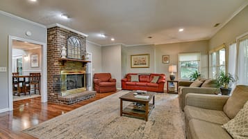 Una sala de estar con chimenea, un sofá rojo, un sofá color beige y una mesa de centro.