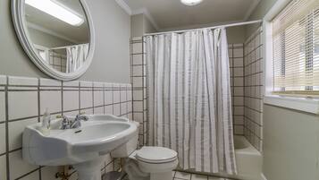 Une salle de bain avec un lavabo blanc, des toilettes et un rideau de douche.