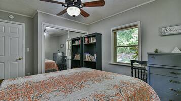 Une chambre à coucher avec un lit, un ventilateur de plafond, une fenêtre et une bibliothèque.