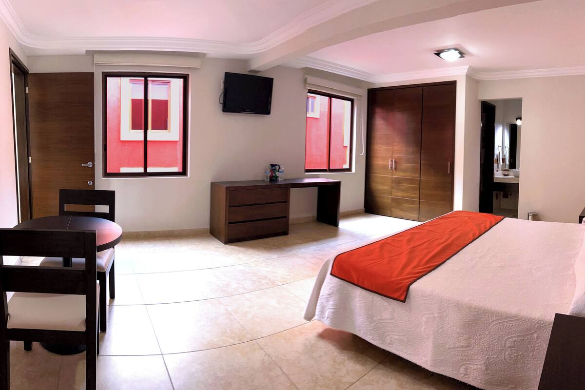 Une chambre à coucher comprenant un lit, un bureau, une chaise, une armoire et un téléviseur.