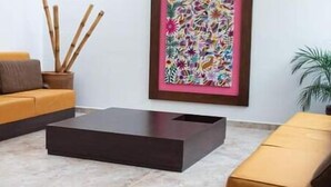 Uma sala de estar moderna com um sofá, uma mesa de centro e uma pintura abstrata emoldurada.