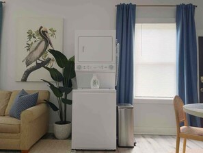 A compact living space with a sofa, a small table, a refrigerator, and a potted plant.