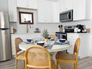 A modern kitchen with white cabinets, a stainless steel refrigerator, a microwave, and a coffee maker.