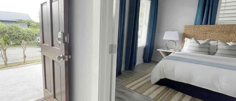 Una habitación de hotel con cama, mesita de noche, lámpara y vistas al exterior.