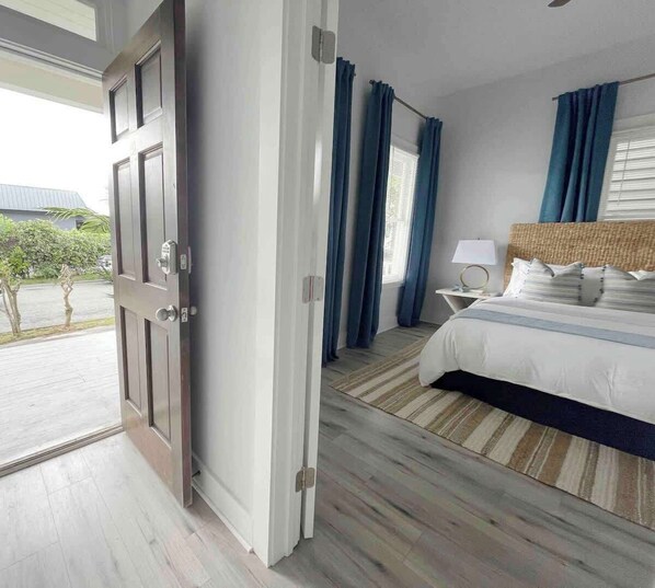 A hotel room with a bed, a nightstand, a lamp, and a view of the outdoors.