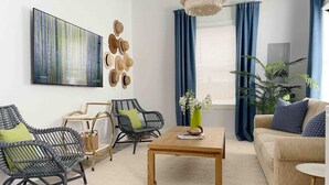Un salón moderno con un cuadro abstracto grande, una mesa de centro de madera y un sofá con cojines azules.