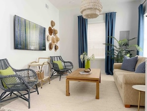 A modern living room with a large abstract painting, a wooden coffee table, and a sofa with blue cushions.