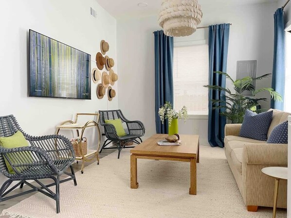 A modern living room with a large abstract painting, a wooden coffee table, and a sofa with blue cushions.