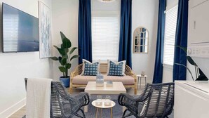 Un salon moderne comprenant un canapé, deux fauteuils, une table basse et un téléviseur.