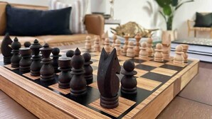 Un tablero de ajedrez con piezas sobre una mesa de madera en una sala de estar.