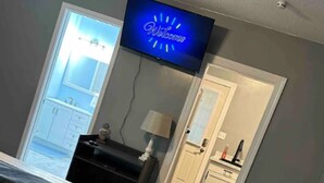 A bedroom with a bed, a desk, a chair, a TV, and a bathroom visible through an open door. - The Blue Dolphin (Beaufort)