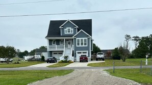 A two-story house with a front porch and a driveway leading to a garage. - The Blue Dolphin (Beaufort)