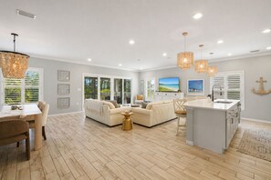 A spacious living area with a sofa, dining table, and kitchen island. - Lux Villa:Pool, Hot Tub, Private Beach, Pickleball (Pensacola)