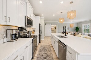 A modern kitchen with white cabinetry, stainless steel appliances, and a central island. - Lux Villa:Pool, Hot Tub, Private Beach, Pickleball (Pensacola)