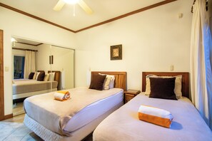 Habitación de hotel con dos camas, un espejo grande, un cuadro en la pared y una ventana con cortinas.