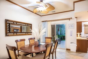 Un comedor con una mesa redonda, sillas, un ventilador de techo, un espejo y vistas al exterior.