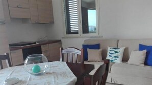 A dining area with a table, chairs, and a glass bowl with an egg. There is a sofa with cushions in the background. - Villa Striari - 5 (Puglia)