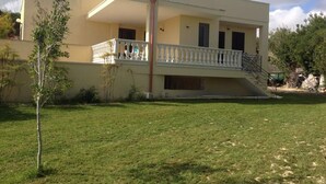 A two-story building with a balcony, a staircase, and a grassy yard. - Villa Striari - 5 (Puglia)
