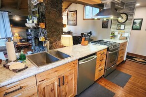 A kitchen with a stone accent wall, stainless steel appliances, and wooden cabinets.