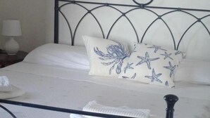 A neatly made bed with a metal headboard, a white pillow with a starfish pattern, and a folded white towel on the bed.